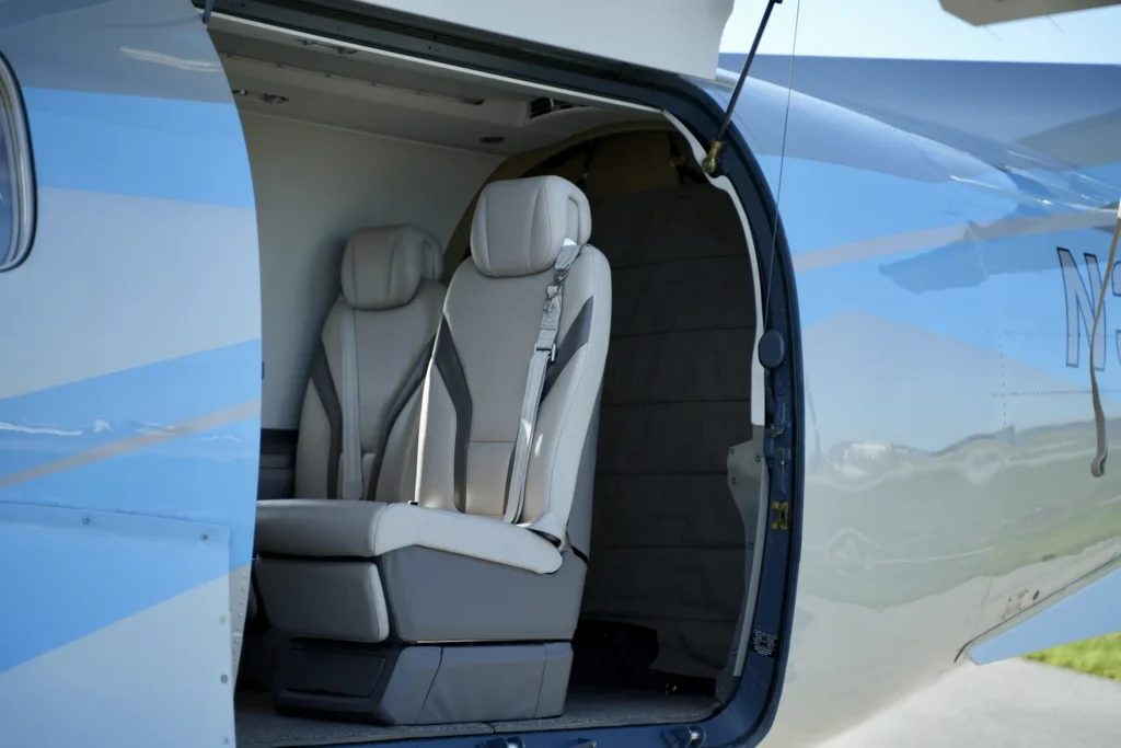 Open cabin door of a Pilatus PC12 NGX showing leather passenger seats.