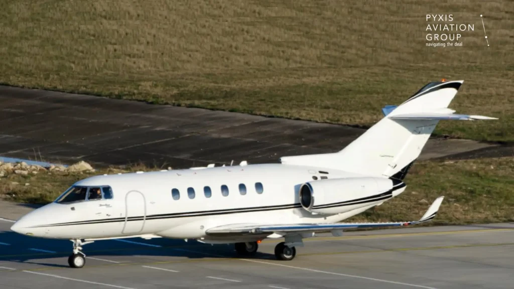WhiteHawker 900XP on an airport taxiway with “Pyxis Aviation Group. Navigating the deal.” in the top right corner. The aircraft is shown in side profile with grassy runway surroundings.